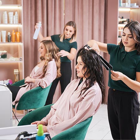 Apprentice hairdressers blow drying haiur
